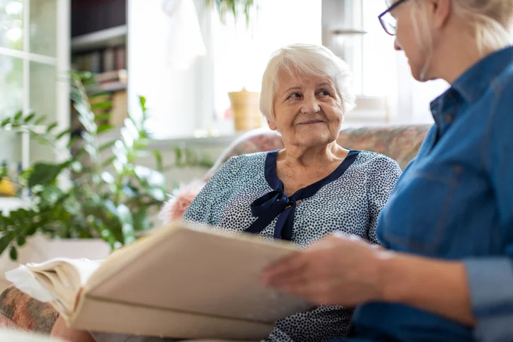 someone helping an elderly lady page through a book