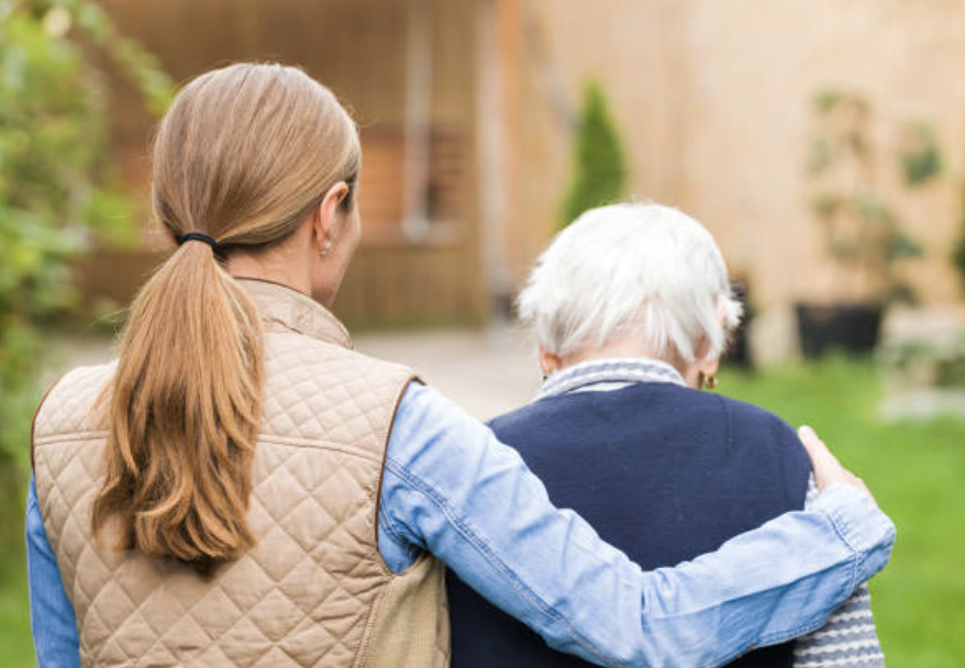 Young carer helping elderly person walk
