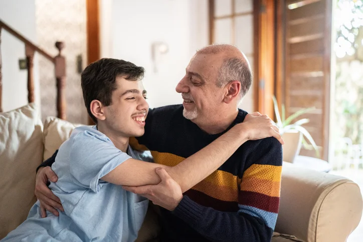 smiling father and son hugging on sofa