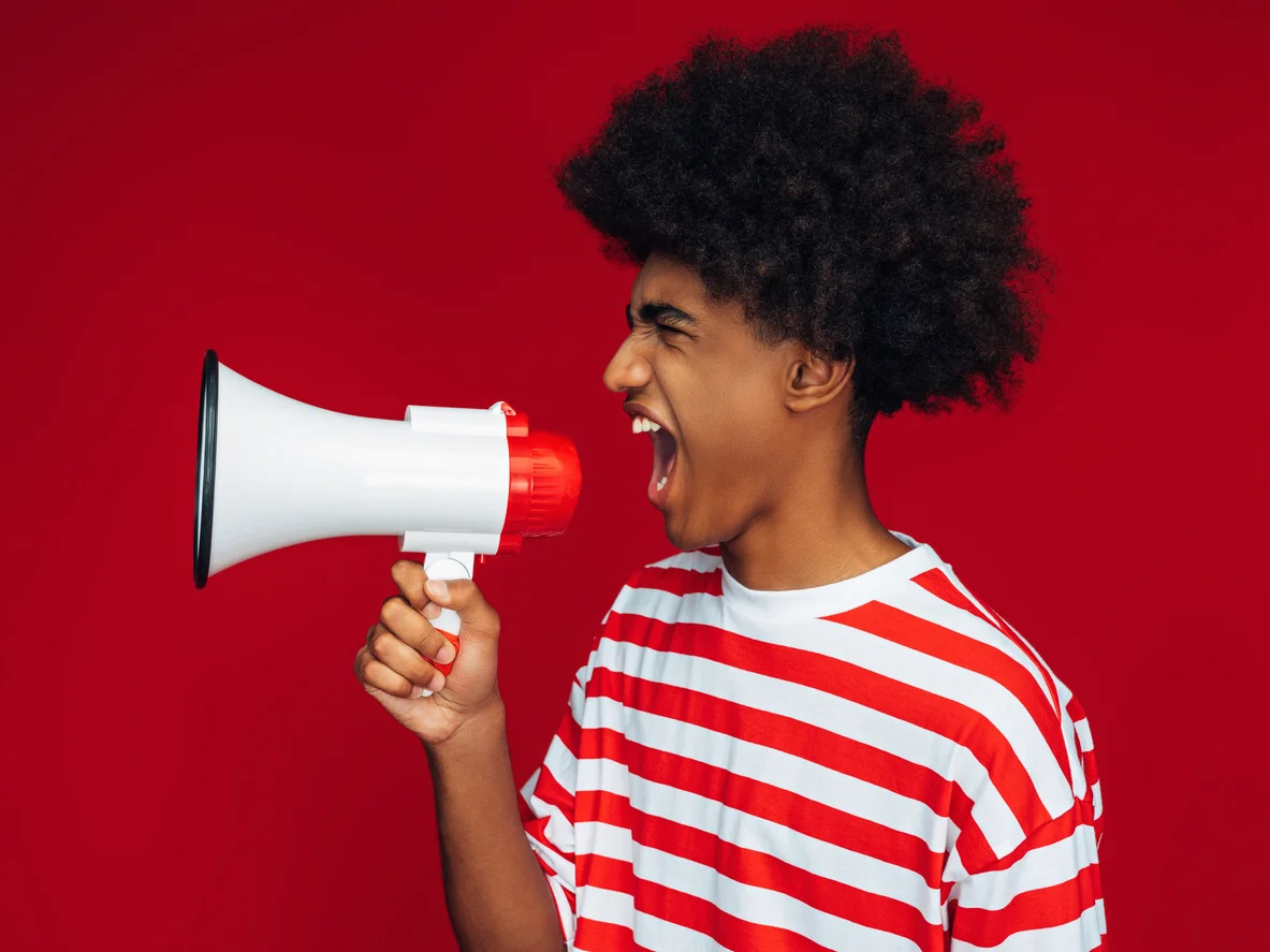 Teenage boy in red and white striped t shirt shouting into megaphone