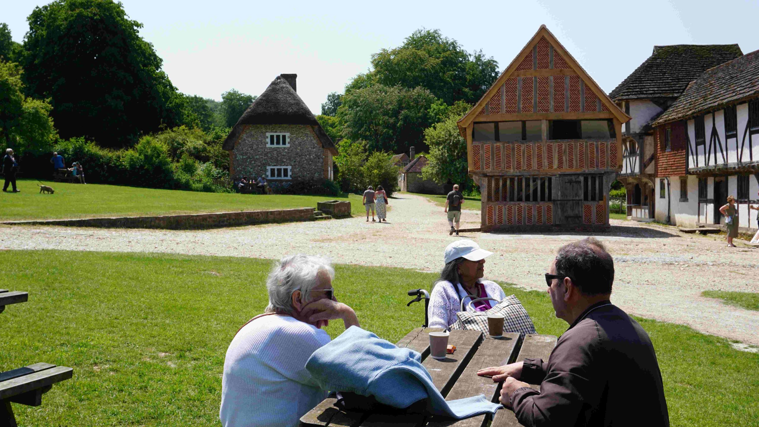 Elderly women with carer sitting at bench near tudor buildings