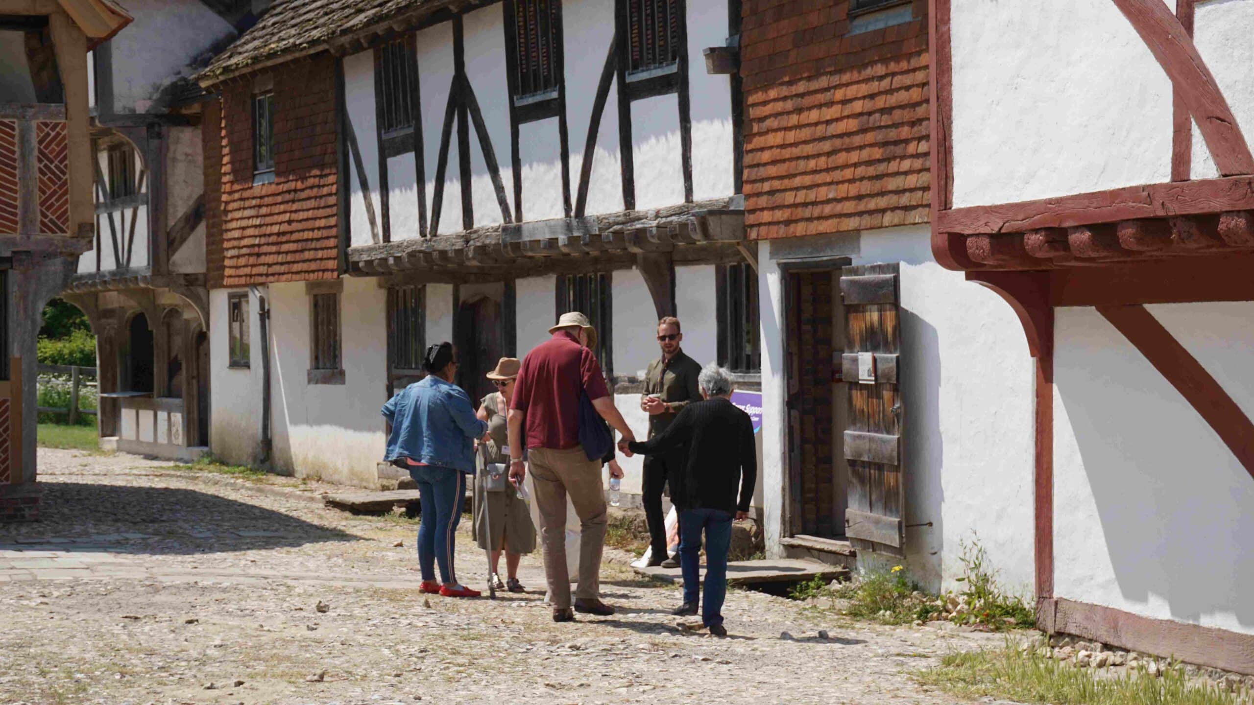 Elderly people with carers being shown around tudor buildings