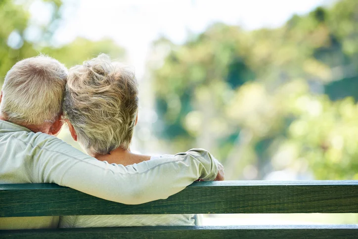 elderly couple on a bench hugging