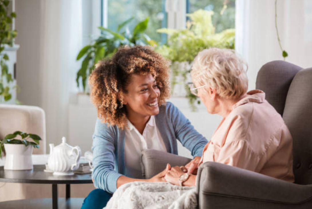 a younger lady smiling and talking with an elderly lady