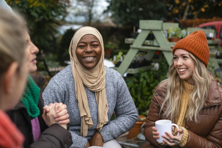 Groups of women sitting in allotment with warm clothes and mugs