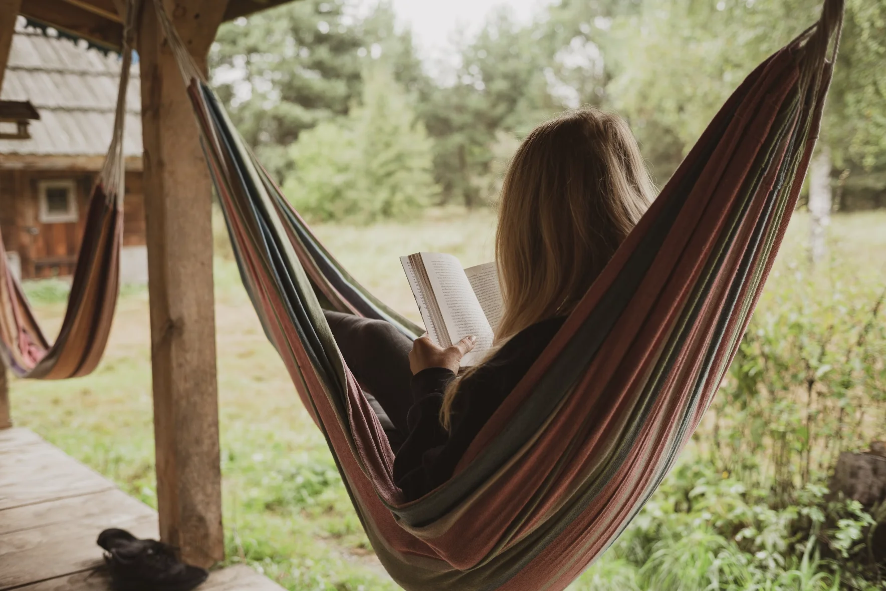 a lady lying in a hammock reading a book