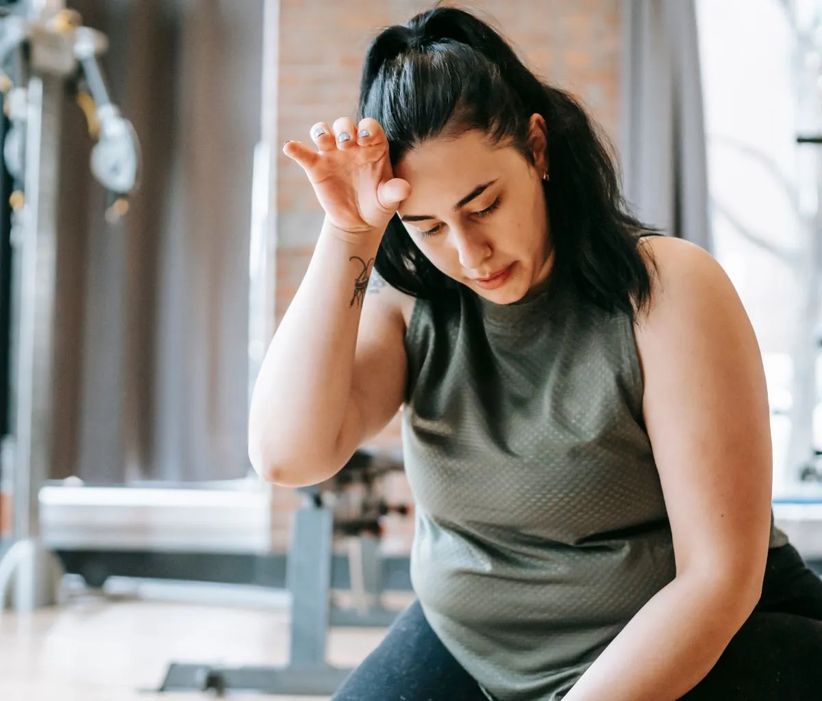 Tired looking woman puts her hand to her forehead