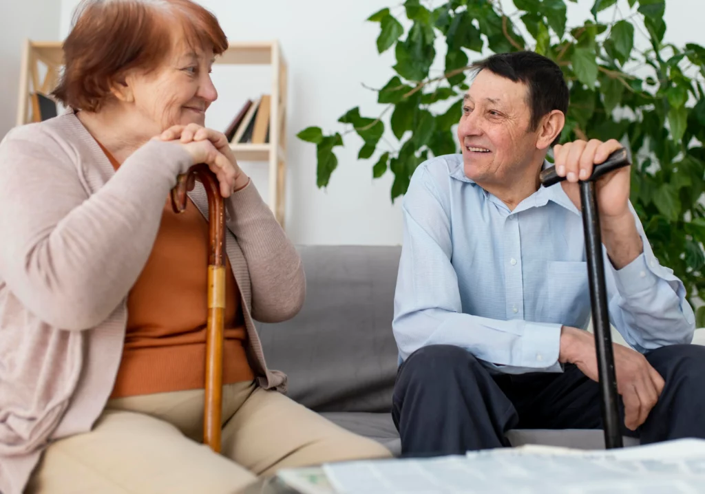 Elderly man and woman sitting side by side with walking sticks