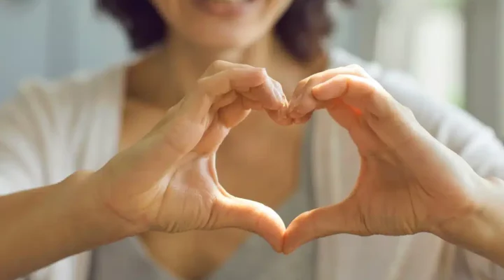 woman holding hands in heart shape