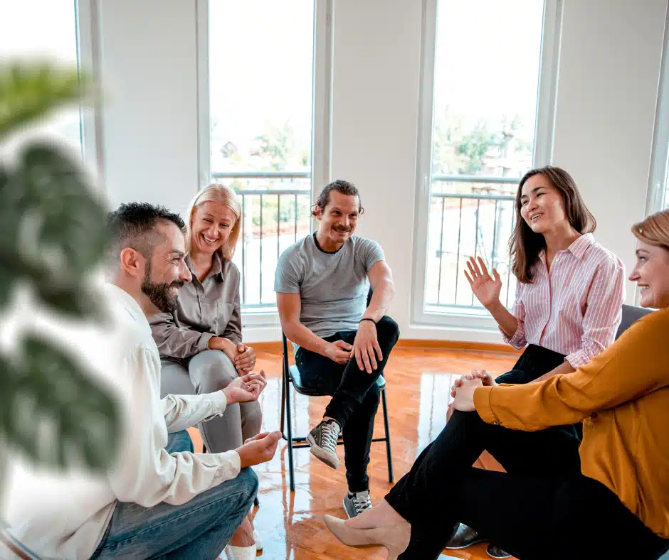 Group of people sitting in circle smiling and talking